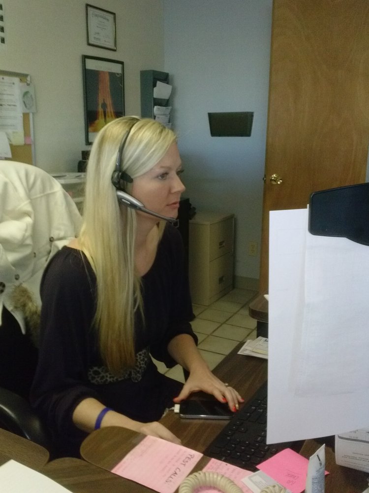 An Acenitec customer service representative on a headset at the office desk